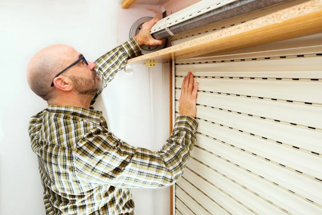 Un technicien répare un volet roulant coincé