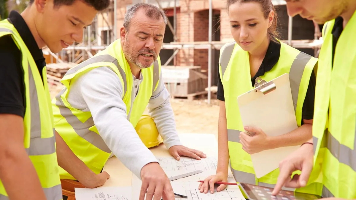 Réunion de chantier avec tableau de suivi des coûts et planning pour illustrer les débouchés du métier.